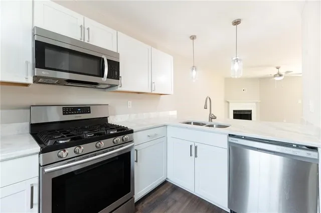 a kitchen with stainless steel appliances granite countertop a sink a stove a microwave and wooden cabinets