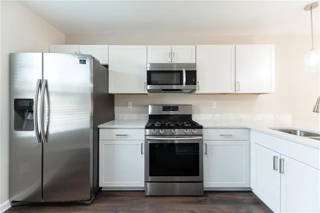 a kitchen with cabinets stainless steel appliances and wooden floor