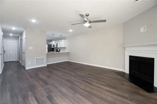 a view of a kitchen and an empty room with wooden floor