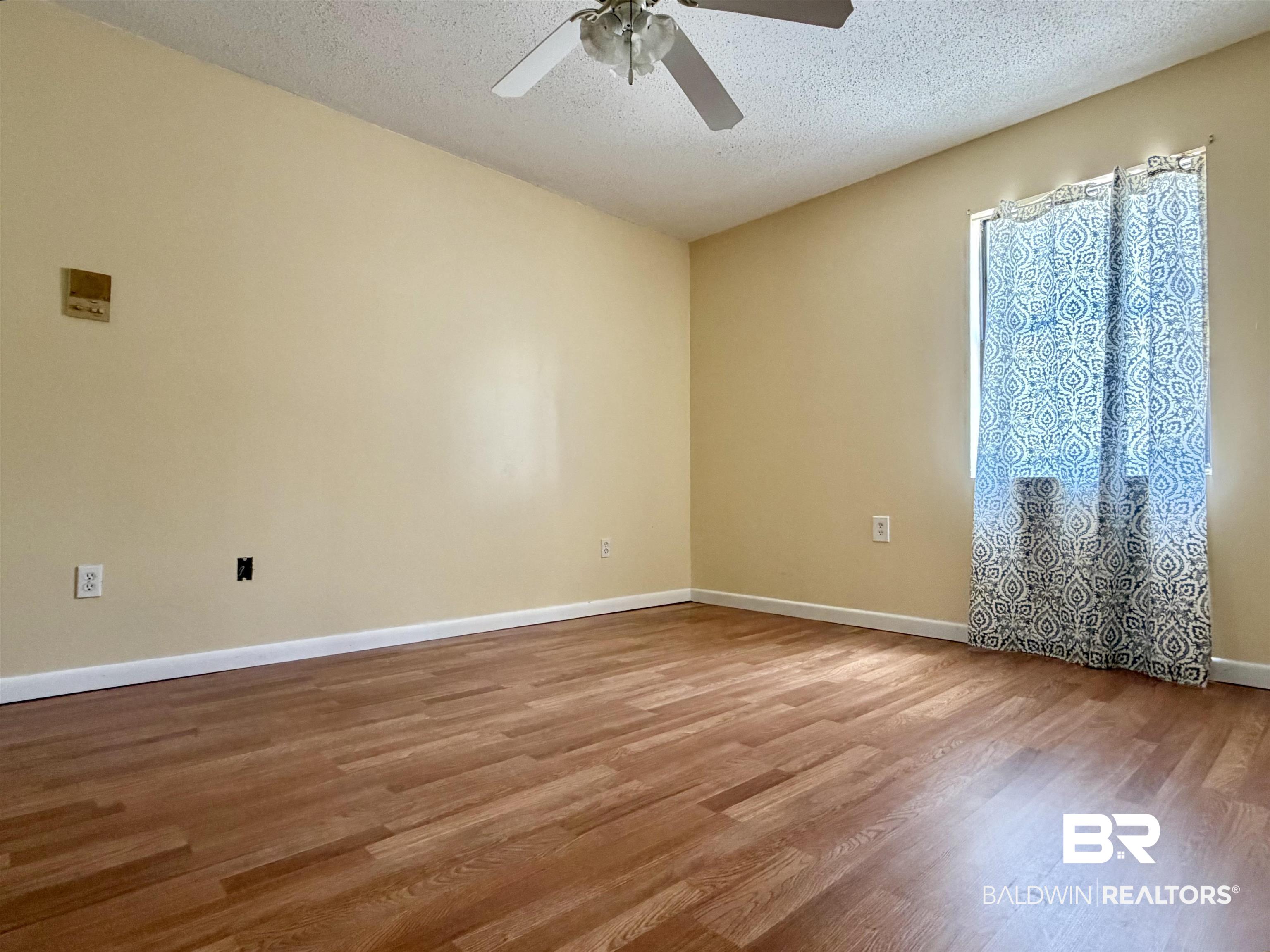 294 Wolf Log Road Flomaton, AL 36441 - Photo 8 of 14 Unfurnished room featuring a ceiling fan, wood finished floors, and a textured ceiling