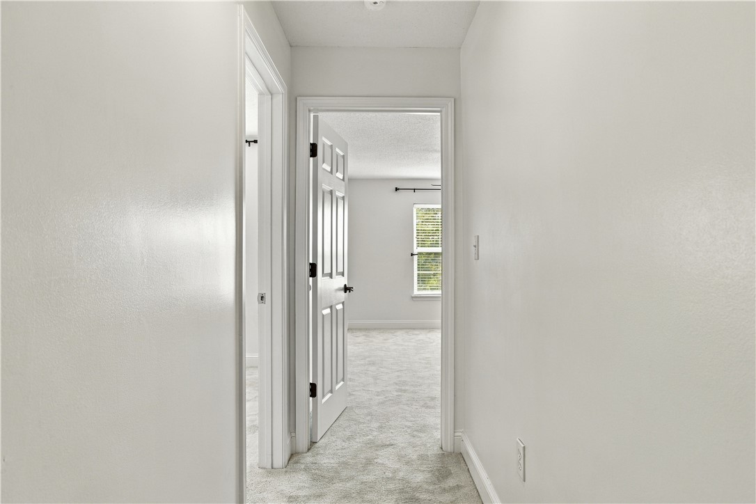 636 Lookover Drive Anderson, SC 29621 - Photo 21 of 34 A neutral hallway with plush carpet floors leads toward a sunlit bedroom.