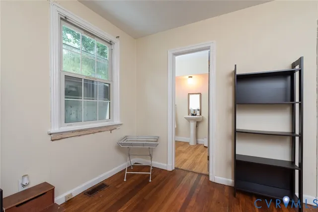 a view of an empty room with a window and wooden floor