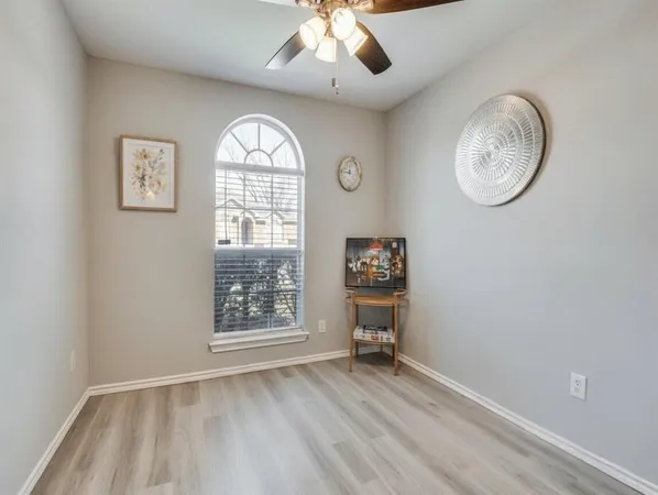 an empty room with wooden floor fan and windows