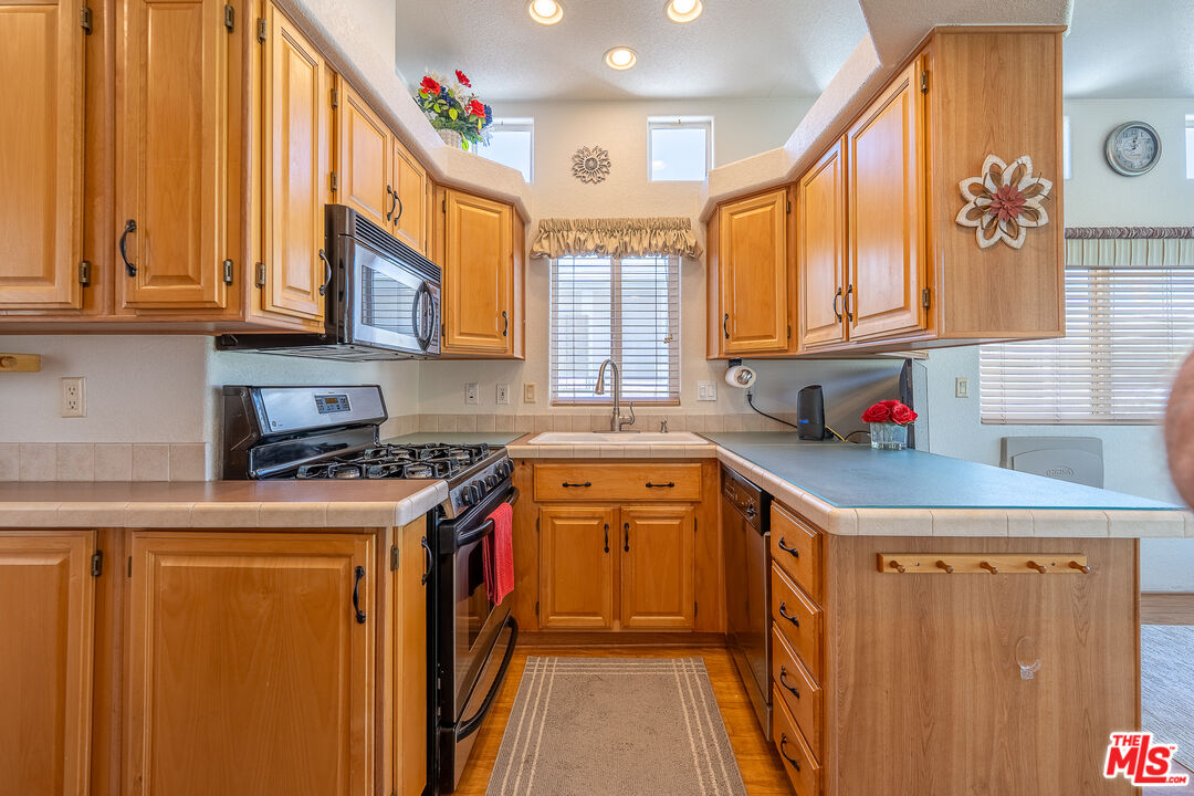 70200 Dillon Road, Unit 581 Desert Hot Springs, CA 92241 - Photo 11 of 23 a kitchen with stainless steel appliances granite countertop a sink a stove and a refrigerator