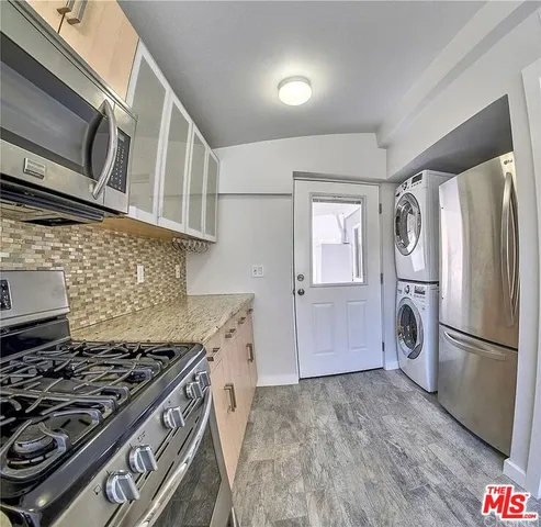 a kitchen with stainless steel appliances granite countertop a sink and cabinets with wooden floor