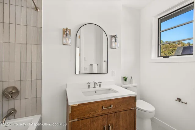 a bathroom with double vanity sink a mirror and a toilet
