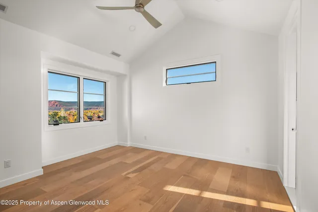 a view of empty room with wooden floor and fan