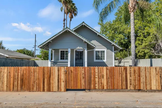 a view of a small house with wooden fence