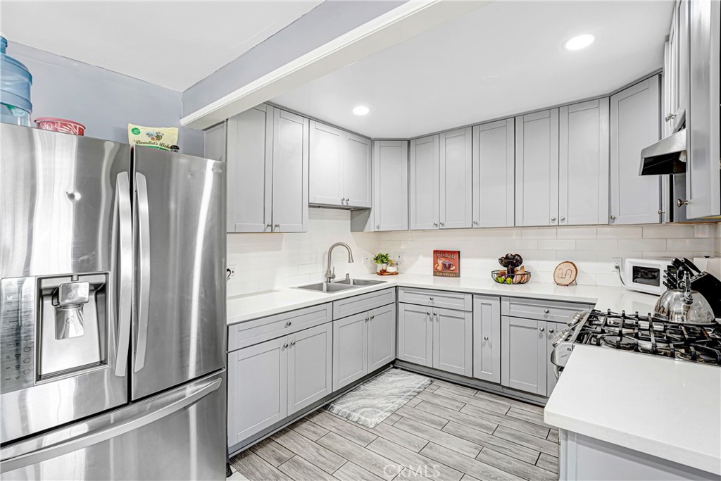 11068 Penrose Street Sun Valley, CA 91352 - Photo 11 of 27 a kitchen with a sink a refrigerator and white cabinets