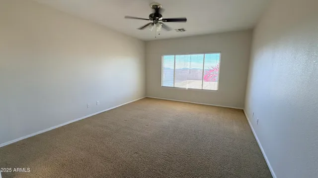 an empty room with a window and a ceiling fan