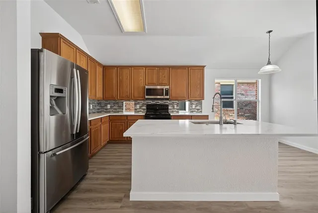 a kitchen with stainless steel appliances a refrigerator and a stove top oven