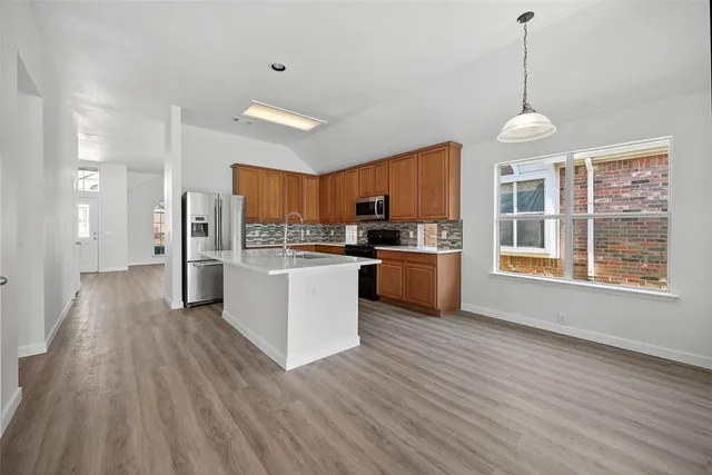 a kitchen with stainless steel appliances kitchen island wooden floors and white cabinets