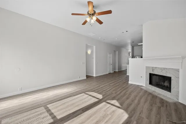 a view of a livingroom with a fireplace a chandelier fan and wooden floor