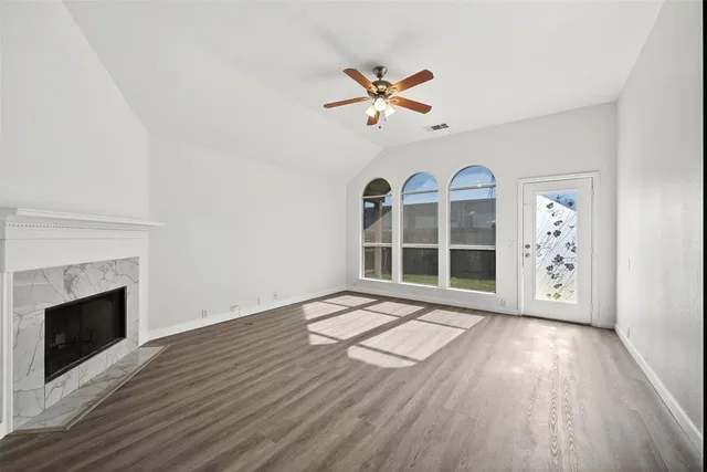 a view of an empty room with a window and wooden floor