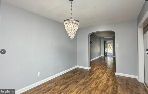 a view of a hallway with wooden floor and a chandelier