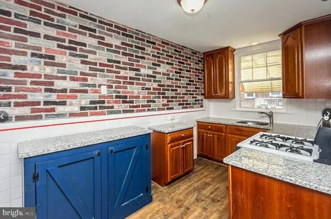 a kitchen with granite countertop stainless steel appliances a sink stove and cabinets