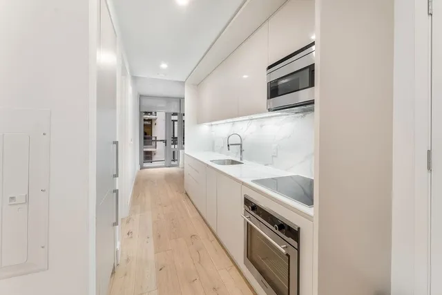 a large white kitchen with a sink stainless steel appliances and cabinets