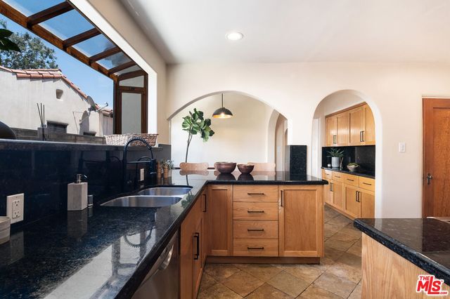 a kitchen with kitchen island granite countertop a stove a sink and a wooden floors