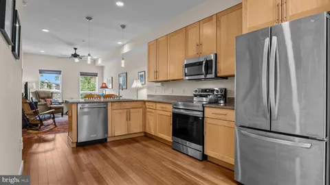a kitchen with stainless steel appliances granite countertop a refrigerator a stove top oven a sink dishwasher and white cabinets with wooden floor