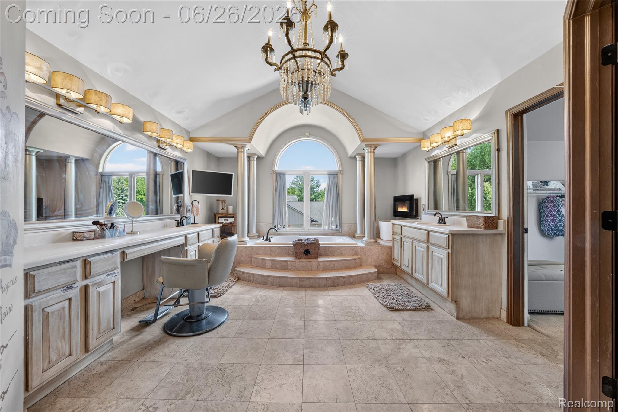 2619 Lambeth Park Rochester, MI 48306 - Photo 34 of 71 Vaulted ceiling bath featuring a central platform soaking tub with arched window, twin vanity stations with extensive countertop space, ornate chandelier, and tiled flooring