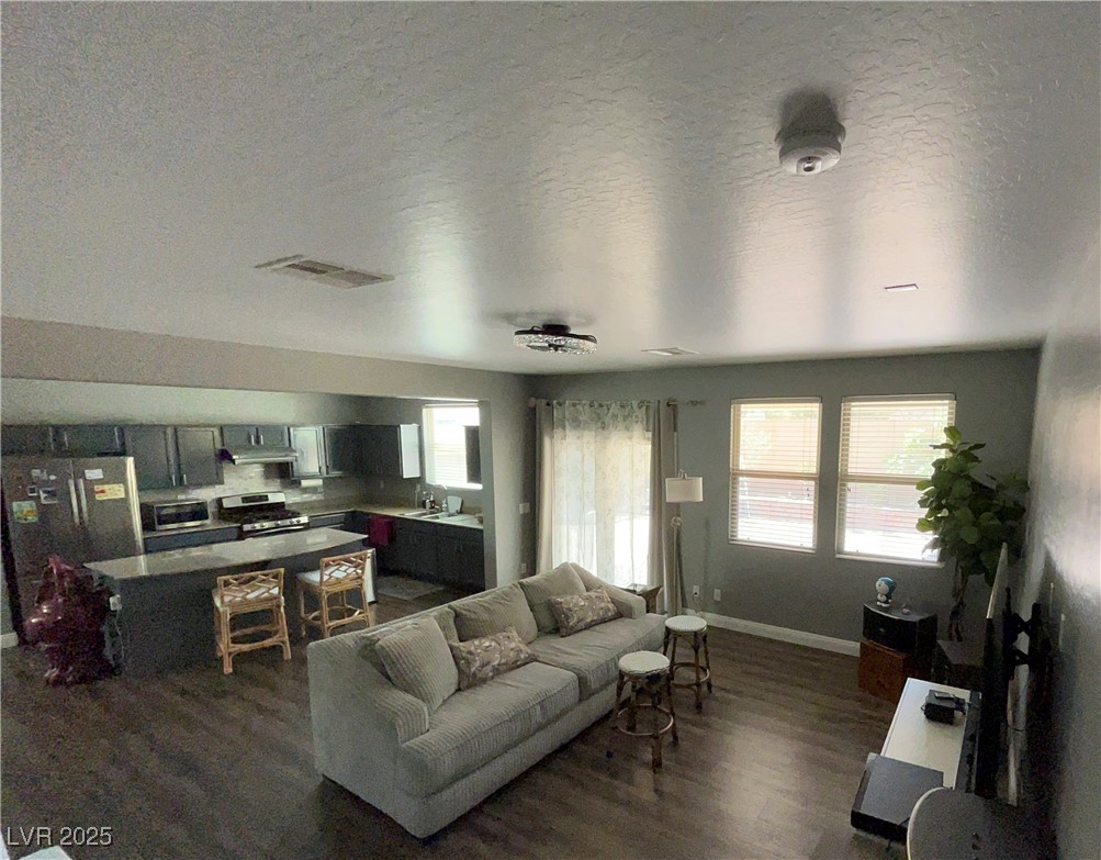 8977 Melridge Road Las Vegas, NV 89148 - Photo 15 of 35 Living area with a healthy amount of sunlight, baseboards, and dark wood-style floors