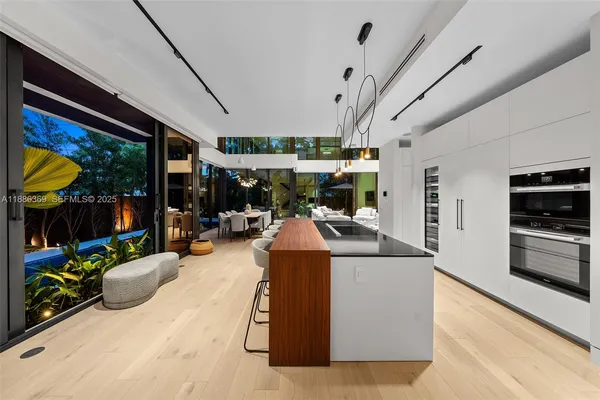 a kitchen with stainless steel appliances kitchen island granite countertop a table chairs in it and a window