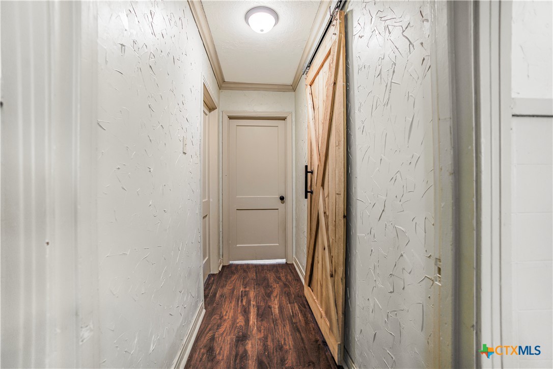 704 Maple Street Yoakum, TX 77995 - Photo 12 of 18 a view of a hallway with wooden floor and a bathroom