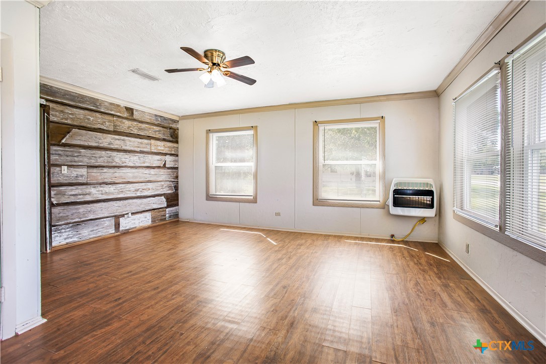 704 Maple Street Yoakum, TX 77995 - Photo 4 of 18 a view of a livingroom with wooden floor a ceiling fan and windows