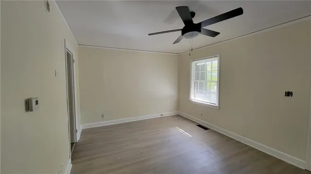 a view of empty room with wooden floor and ceiling fan