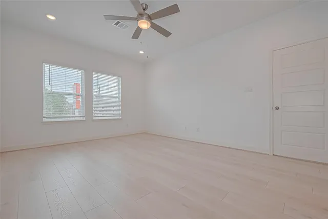 an empty room with windows and fan