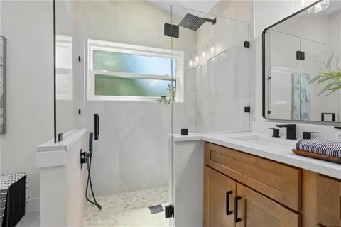a bathroom with a granite countertop sink a mirror and shower
