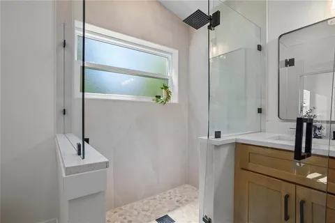 a bathroom with a sink a light fixture and a glass door shower