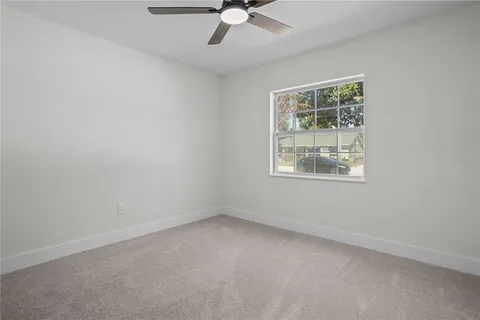 an empty room with a window and a fan