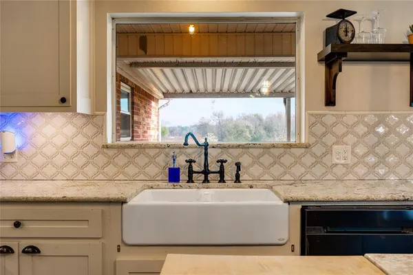 a kitchen with a sink dishwasher a stove and white cabinets with wooden floor
