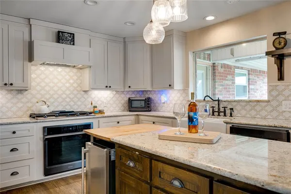 a kitchen with stainless steel appliances kitchen island granite countertop a sink a stove and a wooden floors