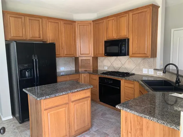 a kitchen with granite countertop stainless steel appliances and wooden cabinets