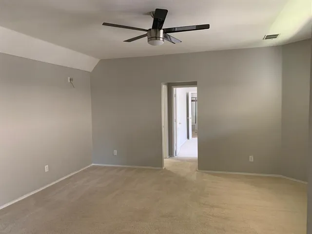 an empty room with windows and fan