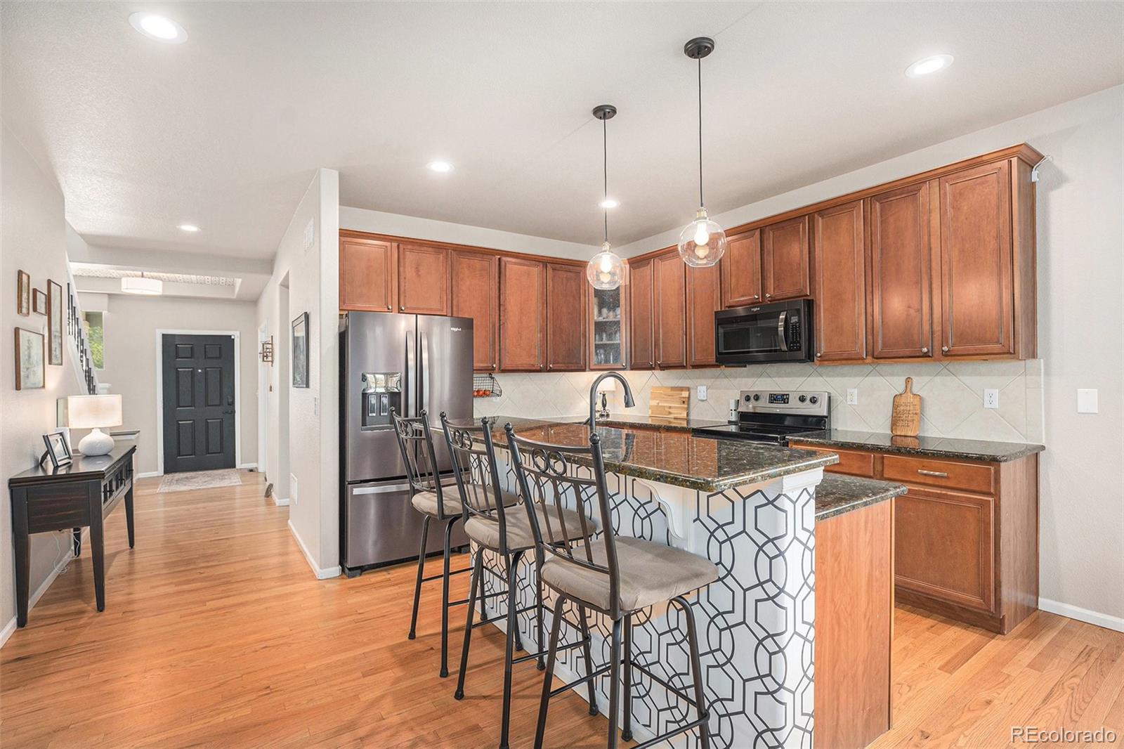 2470 Robindale Way Castle Rock, CO 80109 - Photo 8 of 42 a kitchen with stainless steel appliances granite countertop a refrigerator a stove top oven a sink dishwasher a dining table and chairs with wooden floor