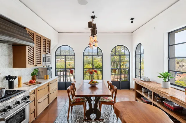 a kitchen with stainless steel appliances a dining table a stove top oven a sink a dining table and chairs with wooden floor