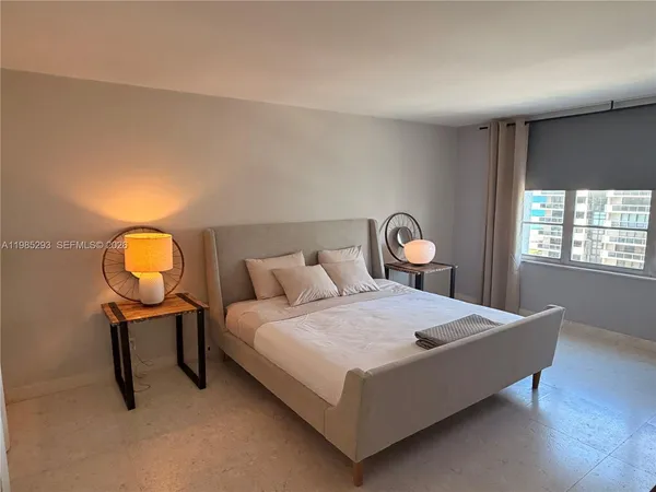 a bedroom with a bed a table and painting on the wall