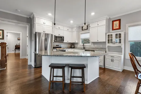 a kitchen with stainless steel appliances kitchen island granite countertop a table chairs refrigerator and sink