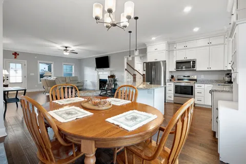 a kitchen with stainless steel appliances granite countertop a stove a refrigerator a kitchen island a table and chairs