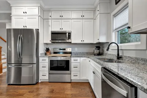 a kitchen with granite countertop a refrigerator stove and sink