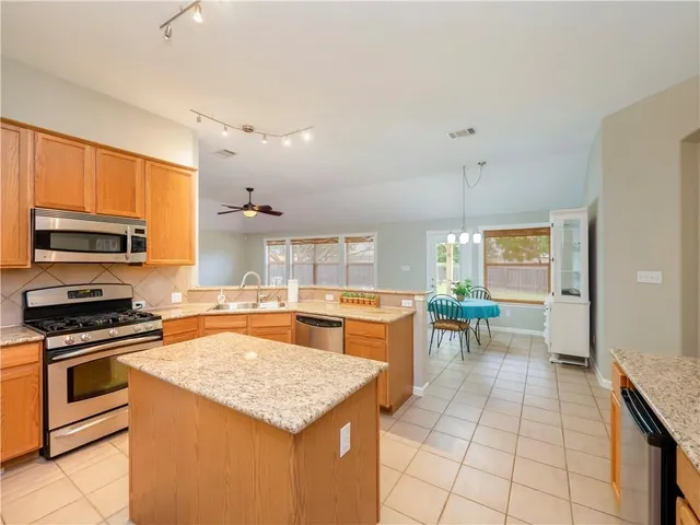 a kitchen with a stove a sink a counter top space and cabinets