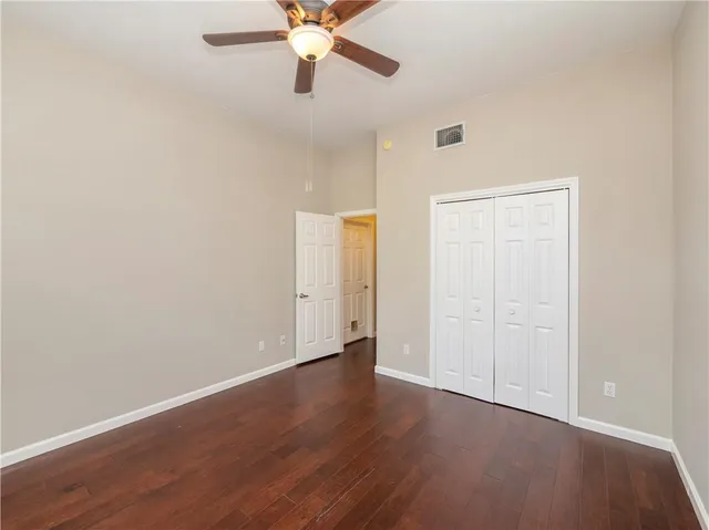 an empty room with wooden floor closet and ceiling fan