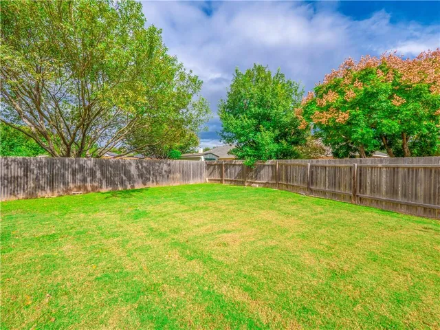 a view of a yard with a fence and trees