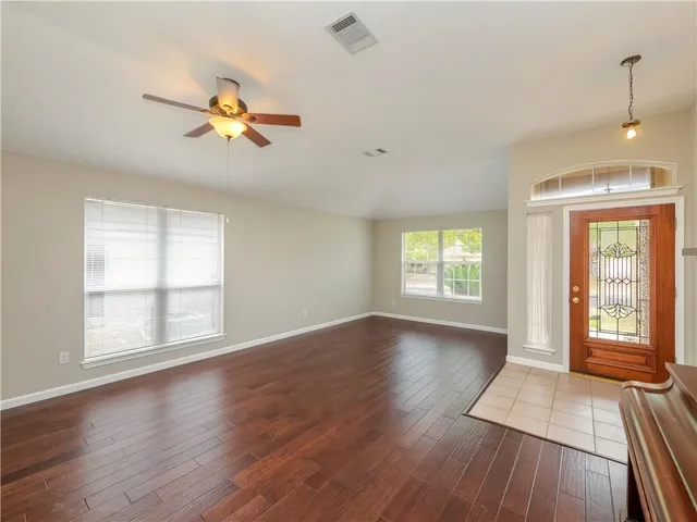 a view of an empty room with a window and wooden floor