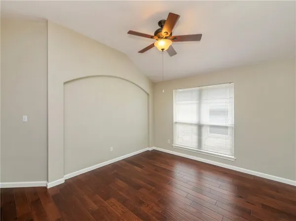 an empty room with wooden floor fan and windows