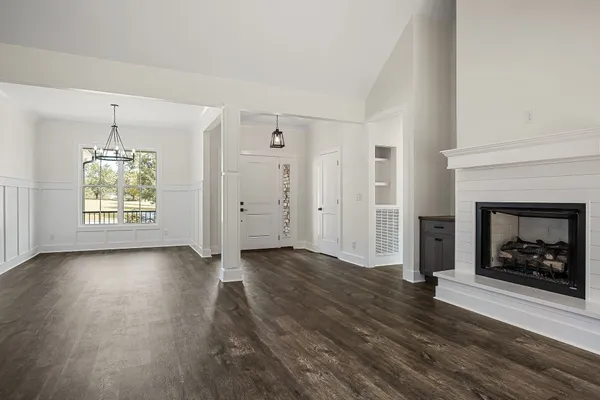 an empty room with wooden floor fireplace and window