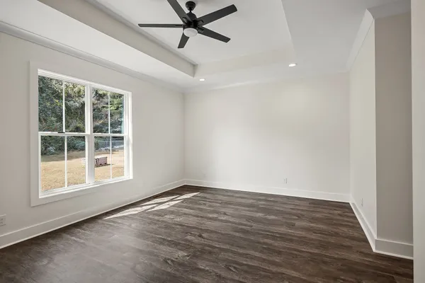 an empty room with wooden floor fan and windows